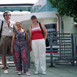 Here's a brief summary of the image: Three people posing outdoors near a building with signage.