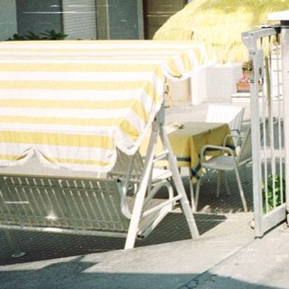 People walk past a cafe on a sunny street.