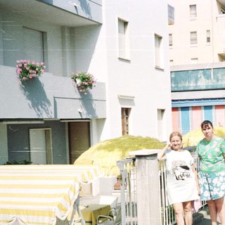 People walk past a cafe on a sunny street.