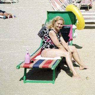 Crowded beach scene with people sunbathing and relaxing.