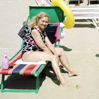 Crowded beach scene with people sunbathing and relaxing.