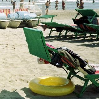 Couple stands on a crowded beach near the ocean.