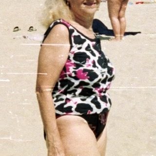 Crowded beach scene with a woman walking toward the viewer.
