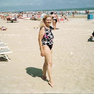 Crowded beach scene with a woman walking toward the viewer.