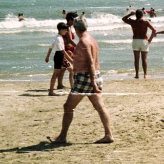 People on a beach with waves and clear sky.