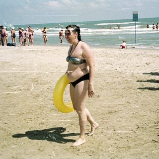 People on a beach with a woman holding a floatie.