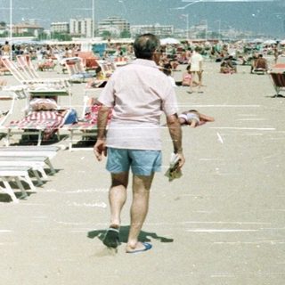 Crowded beach with many sunbathers and beach umbrellas.