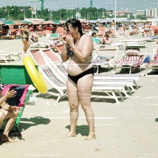 Crowded beach with many sunbathers and beach umbrellas.