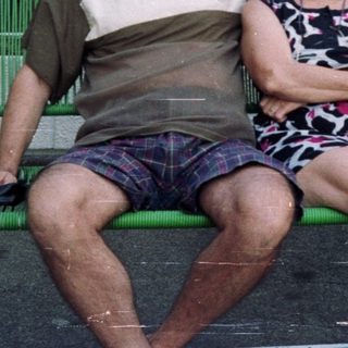 Couple sits on a swing in a garden setting.