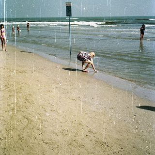 People on a beach with waves and a sign.