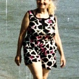 Woman walking on a crowded beach with the ocean behind.