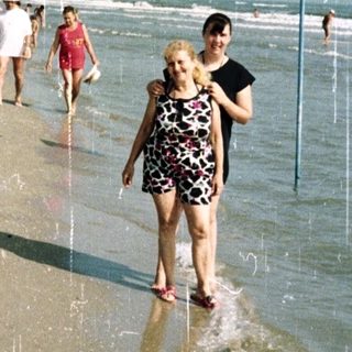Couple walks on a beach during a rain shower.