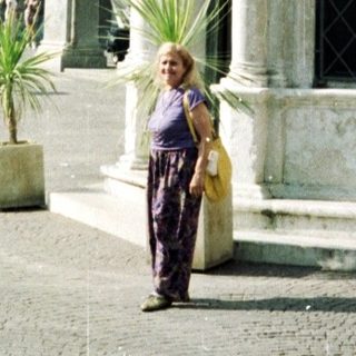 Woman stands in a square with historic buildings.