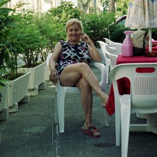 Woman seated at a table outside a hotel.