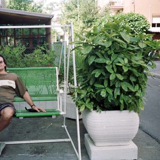 Man sits on a swing outside a house.