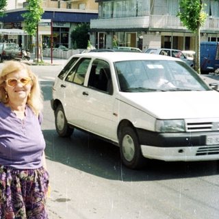 Woman in patterned pants stands on a city street.