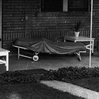 Black and white image of a porch with furniture.