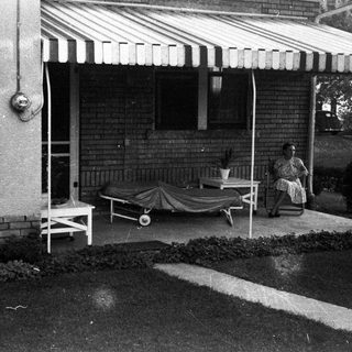 Black and white image of a porch with furniture.