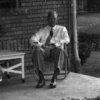 Man seated on porch, relaxing in a vintage setting.