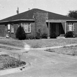 Black and white photo of a modest brick house.