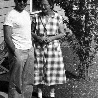 Couple stands outside a vintage home with a garden.