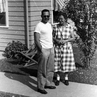 Couple stands outside a vintage home with a garden.