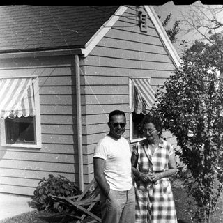 Couple stands outside a vintage home with a garden.