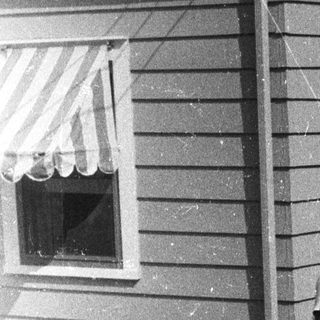 Couple stands outside a vintage home with a garden.