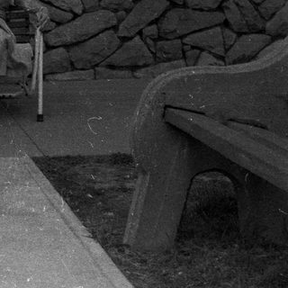 Woman sits on a chair outside a stone building.