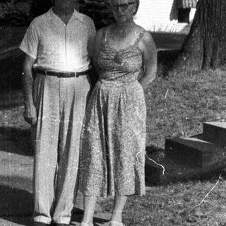 Older couple stands on a pathway in a garden.