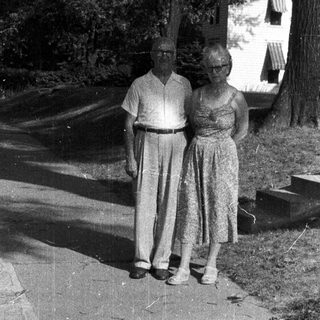 Older couple stands on a pathway in a garden.