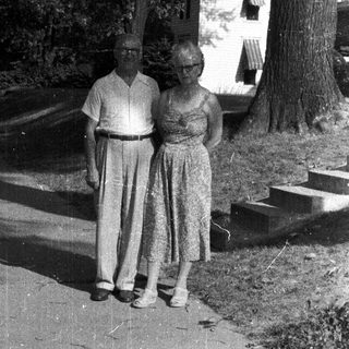 Older couple stands on a pathway in a garden.
