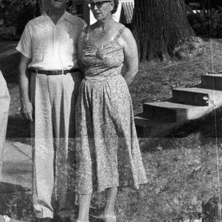 Black and white photo of a family standing near a house.