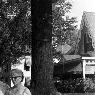 Black and white photo of a family standing near a house.