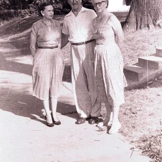 Here's a brief summary of the image: Couple and woman walking on a path outdoors.