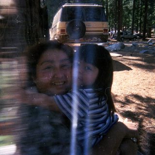 Girl looking through a window, camping scene in background.