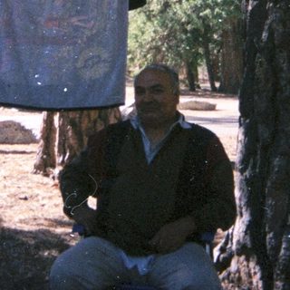 People relaxing outdoors with laundry hanging between trees.