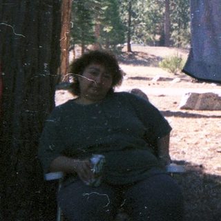 People relaxing outdoors with laundry hanging between trees.