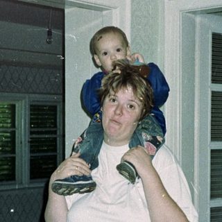 Woman carries a child on her shoulders inside.