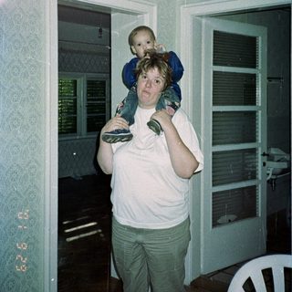 Woman carries a child on her shoulders inside.