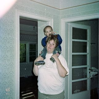 Woman carries a child on her shoulders inside.
