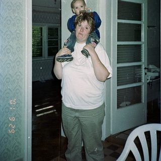 Woman carries a child on her shoulders inside.