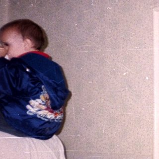 Man holding baby in doorway with wallpaper and light fixture.