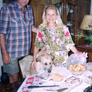 Couple and dog near a table with food and decor.