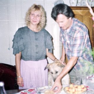 Couple and dog near table with food and plants.