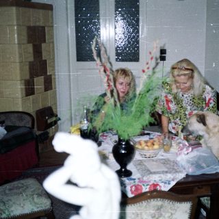 Two women at a table with a dog and decor.