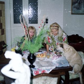 Two women at a table with a dog and decor.