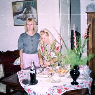 Two women standing near a table with food and decor.