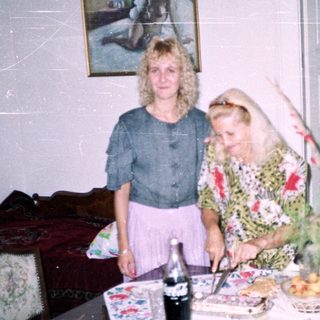 Two women standing near a table with food and decor.