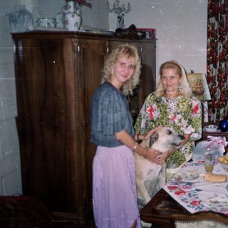 Woman and elderly woman with dog in a decorated room.